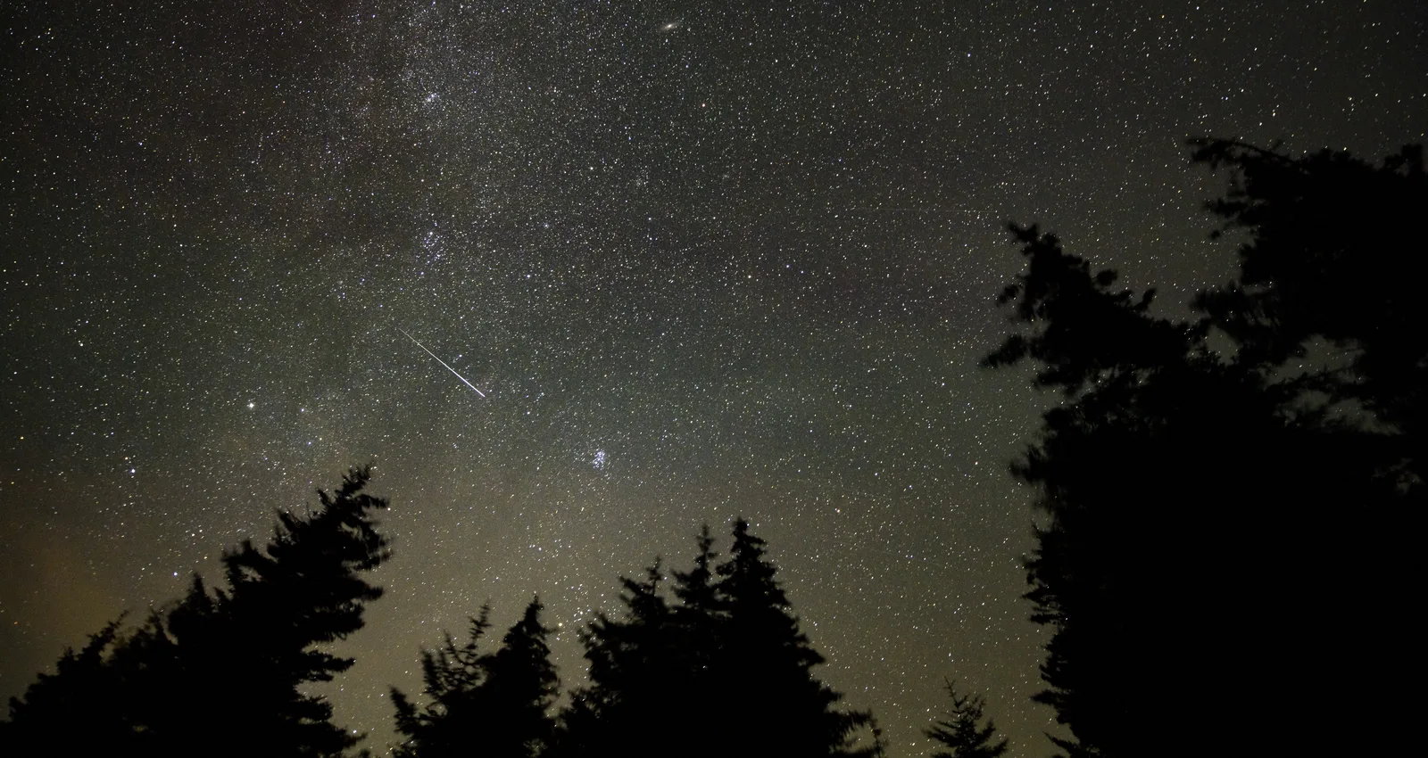 夜空を長時間露光で撮影し、流星が光の筋となって横切っている写真