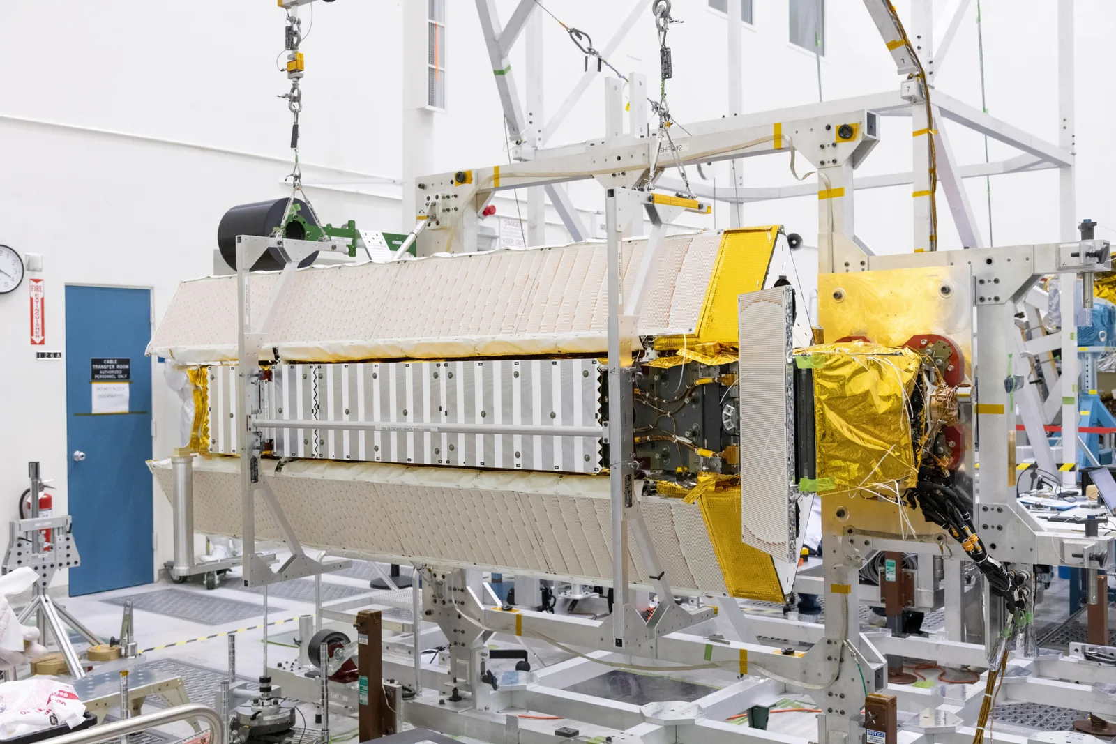 クリーンルーム内で組み立て中の人工衛星と試験設備