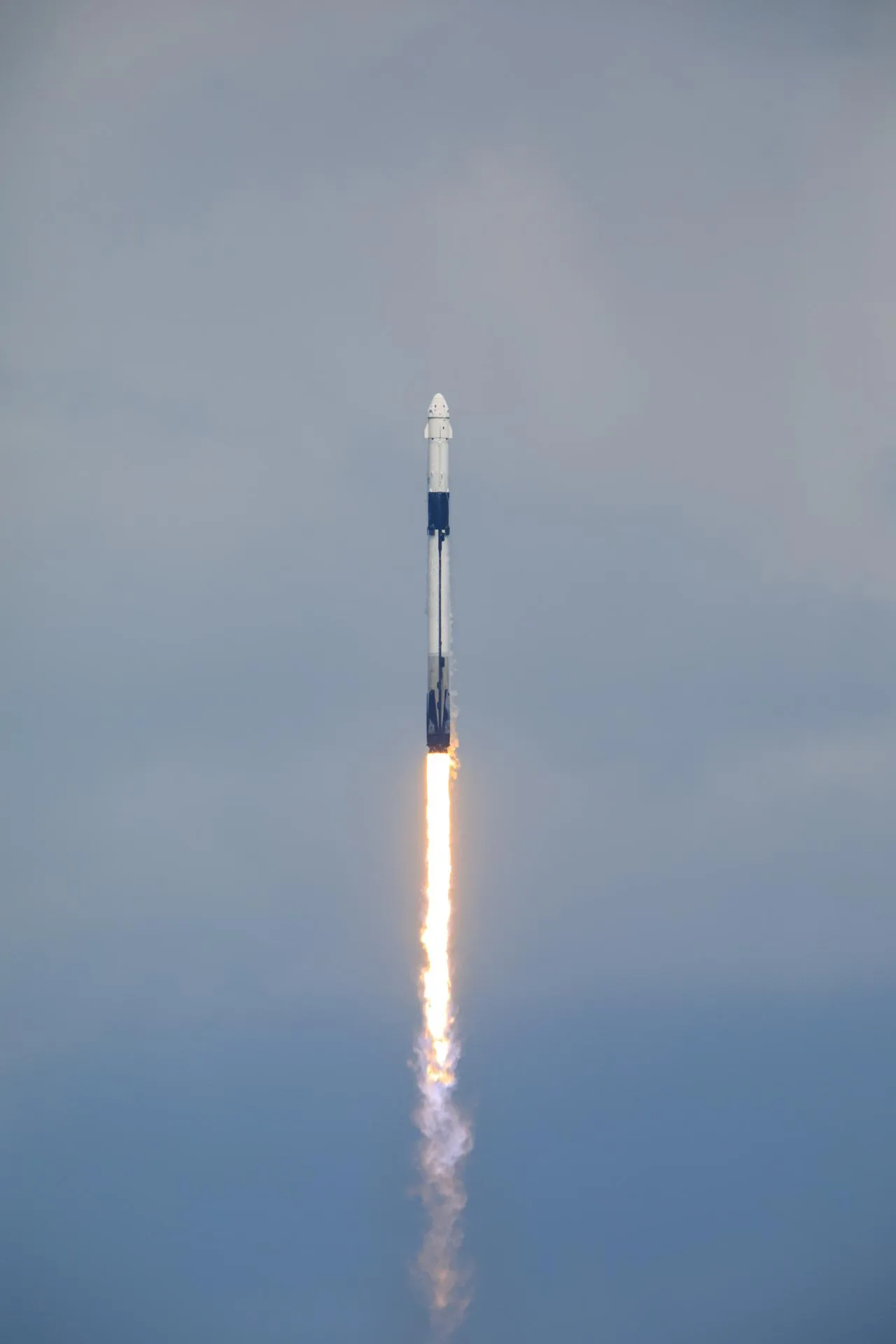射場から夜空へ上昇する商業乗員輸送のロケット